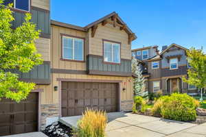 Craftsman-style house featuring board and batten siding, stone siding, an attached garage, and driveway