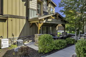 View of exterior entry featuring board and batten siding, stone siding, and covered porch