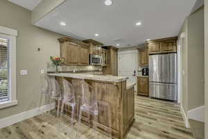 Kitchen featuring appliances with stainless steel finishes, a breakfast bar, tasteful backsplash, a peninsula, and recessed lighting