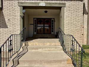 View of exterior entry featuring brick siding and a porch