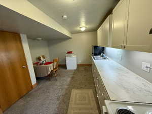 Kitchen with light countertops, dark carpet, a textured ceiling, freestanding refrigerator, and white cabinetry