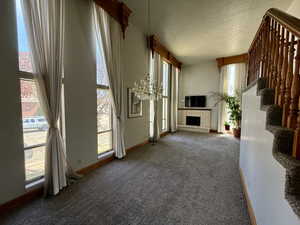 Unfurnished living room with carpet floors, stairway, a textured ceiling, and a fireplace
