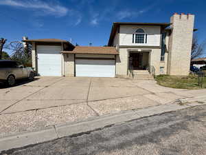 Traditional-style home with a garage, driveway, brick siding, a chimney, and roof with shingles