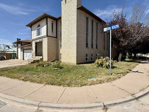 View of side of home with a garage, brick siding, a yard, and concrete driveway