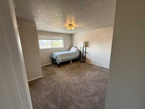 Carpeted bedroom with a textured ceiling and baseboards