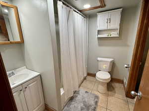 Full bath with shower / bathtub combination with curtain, vanity, and light tile patterned floors