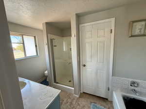 Bathroom with vanity, a textured ceiling, a shower stall, a bath, and light tile patterned floors
