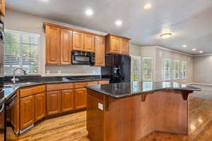 Kitchen featuring dark stone counters, recessed lighting, light wood-style flooring, and brown cabinets