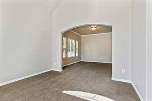 Dining Room with arched walkways, carpet flooring, crown molding, and high vaulted ceiling
