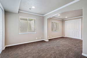 bedroom with a closet,  carpet, arched walkways, ornamental molding, and recessed lighting