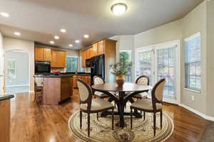 Dining room featuring arched walkways, light wood finished floors, and recessed lighting