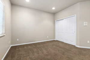Unfurnished bedroom featuring dark carpet, a closet, and recessed lighting