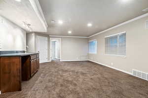 Basement family room featuring dark carpet, recessed lighting, a textured ceiling, and ornamental molding