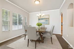 Carpeted dining space featuring crown molding, arched walkways, and a chandelier
