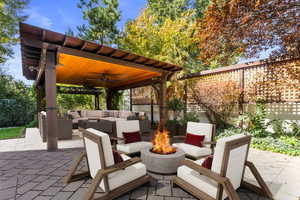 Fenced backyard featuring a patio area, an outdoor living space with a fire pit, and a ceiling fan