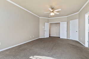 Primary bedroom featuring crown molding, carpet floors, and ceiling fan