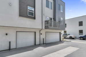 Rear view of house with a balcony, an attached garage, and stucco siding