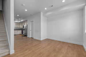 Unfurnished living room with stairs, recessed lighting, and light wood-style floors