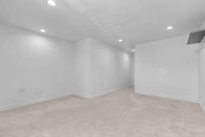 Below grade area featuring recessed lighting and light carpet