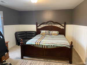 Bedroom featuring wainscoting, carpet floors, and a decorative wall