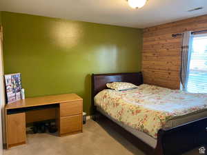 Bedroom featuring light colored carpet and wooden walls