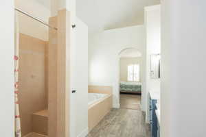 Ensuite bathroom with a stall shower, vanity, wood finish floors, and a bath