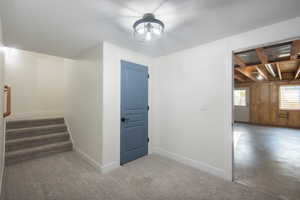 Hall with stairway, concrete floors, and carpet flooring