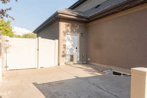Property entrance featuring a gate, stucco siding, a patio, and a shingled roof
