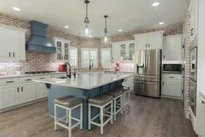 Kitchen with appliances with stainless steel finishes, a kitchen breakfast bar, custom exhaust hood, recessed lighting, and blue cabinetry
