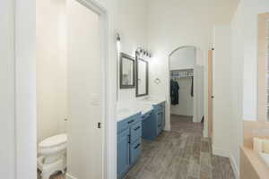 Full bath featuring double vanity, wood tiled floors, a bath, and a walk in closet