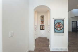 Hall with wood finished floors and arched walkways