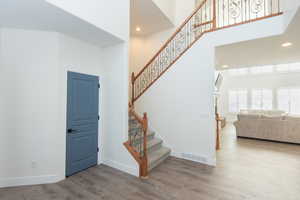 Stairs with wood finished floors, recessed lighting, and a towering ceiling