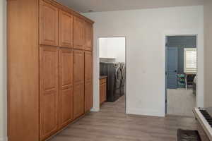 Corridor featuring light wood-style floors and washer and dryer