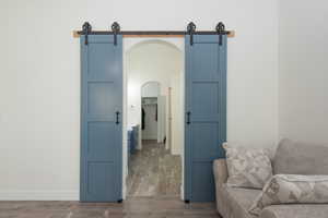 Sitting room featuring a barn door, wood finished floors, and arched walkways