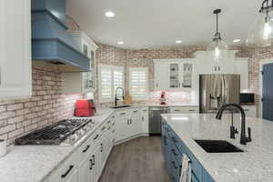 Kitchen featuring blue cabinetry, glass insert cabinets, white cabinets, light stone countertops, and recessed lighting