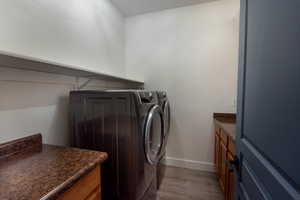 Laundry room featuring light wood finished floors, cabinet space, and washing machine and dryer