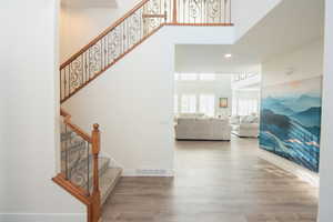 Staircase featuring wood finished floors, recessed lighting, and a high ceiling