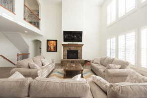 Living area with a towering ceiling, a fireplace, wood finished floors, and arched walkways