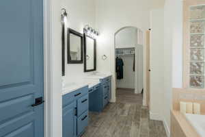 Bathroom featuring double vanity, wood tiled floors, and a bath