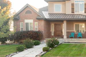 View of front of property featuring brick siding, a front lawn, and a standing seam roof