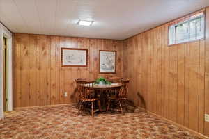 Carpeted dining area featuring wooden walls