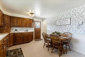 Dining space featuring wainscoting, light colored carpet, and wallpapered walls