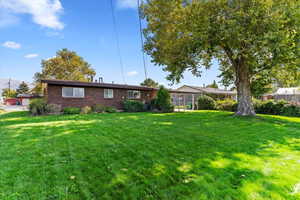 Back of property with a lawn and brick siding