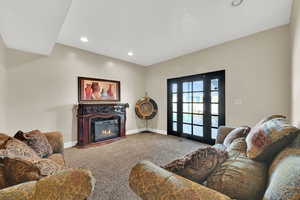 Carpeted living area featuring a glass covered fireplace and recessed lighting