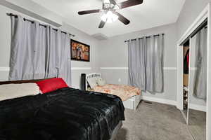 Carpeted bedroom with a ceiling fan and a closet