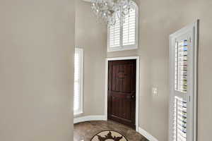 Foyer entrance featuring plenty of natural light, a towering ceiling, and a chandelier