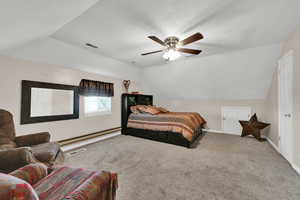 Bedroom with light colored carpet, vaulted ceiling, a baseboard heating unit, and ceiling fan