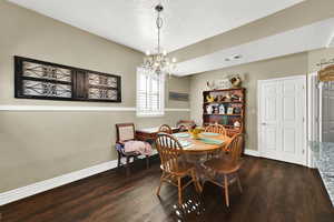 Dining space with a textured ceiling, dark wood-type flooring, and a chandelier