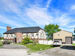 View of front facade with a garage, a chimney, and an outbuilding