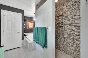 Bathroom featuring light tile patterned floors, a bath, and a textured ceiling